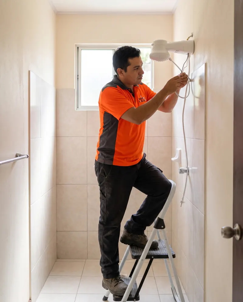 Técnico instalando una ducha eléctrica en un baño